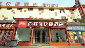 A hotel facade with a red and yellow color scheme, multiple windows, and a visible entrance. - Shankee Hotel (Linyi Baishabu) (Linyi)