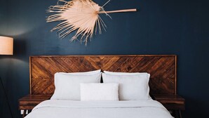 Ein Schlafzimmer mit einem Holzkopfteil, weißer Bettwäsche und einem dekorativen Wandventilator.