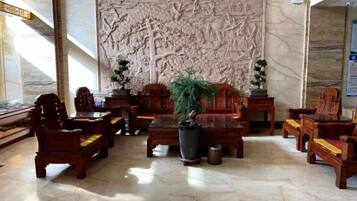Un hall d’entrée avec des meubles en bois de style traditionnel, un grand panneau mural sculpté et une plante en pot.