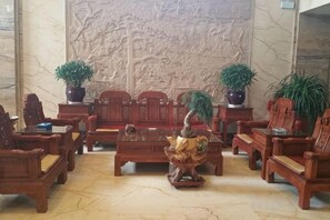 A traditional room with wooden furniture, a decorative wall, and potted plants. - KAIYUE HOTEL (Qiemo)
