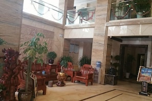 A lobby with marble floors, wooden furniture, potted plants, and a high ceiling. - KAIYUE HOTEL (Qiemo)