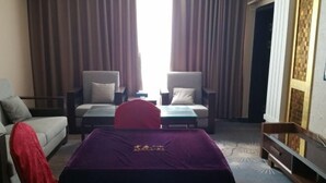 A hotel room with a bed, a sofa, a small table, and a TV. - KAIYUE HOTEL (Qiemo)