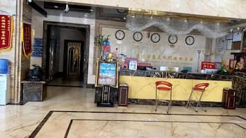 Un hall d’hôtel avec un sol en marbre, un comptoir d’accueil et une horloge murale.