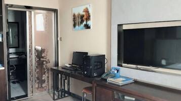 Habitación de hotel con escritorio, televisión, cama y puerta corrediza que da a un balcón.
