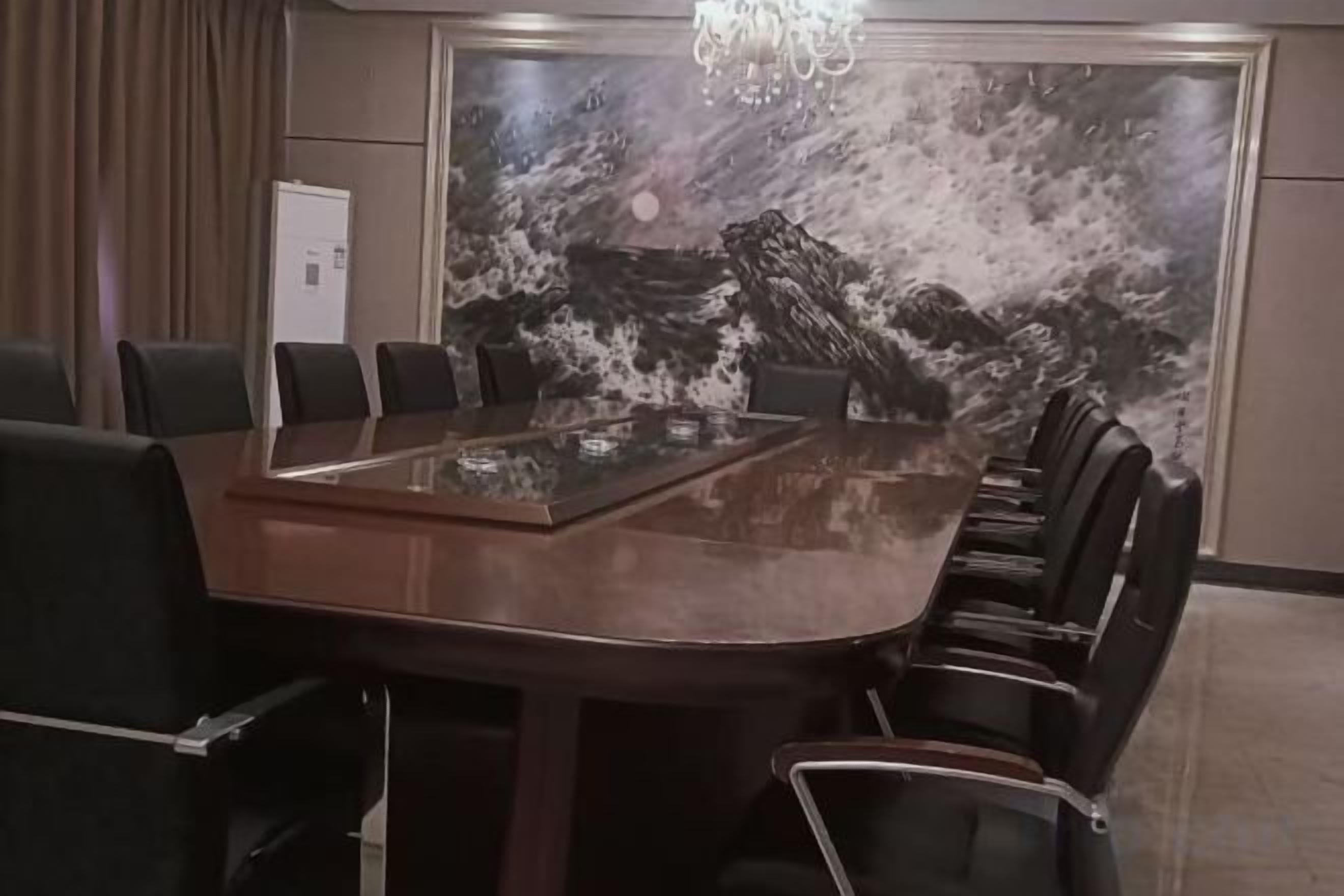 Een vergaderzaal met een grote ovale tafel, zwarte stoelen en een muurschildering.