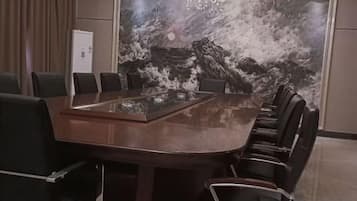 Een vergaderzaal met een grote ovale tafel, zwarte stoelen en een muurschildering.