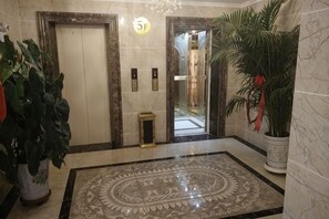 Eine Lobby mit Marmorböden, einem großen dekorativen Fliesenmuster, einer Topfpflanze und einer Tür mit einer Nummer.