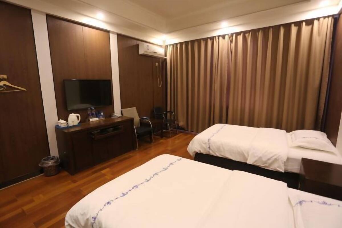 Habitación de hotel con dos camas, un escritorio con televisor, una silla y un armario.