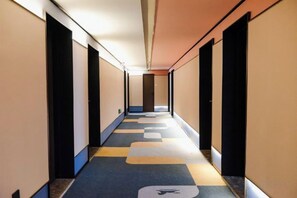 A hotel corridor with a checkered carpet, doors on both sides, and a ceiling light fixture. - HanTing Hotel (Tianjin Railway Station Italian Style Street) (Tianjin)