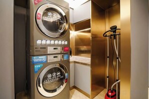 Un cuarto de lavado pequeño con dos lavadoras apiladas y un tendedero.