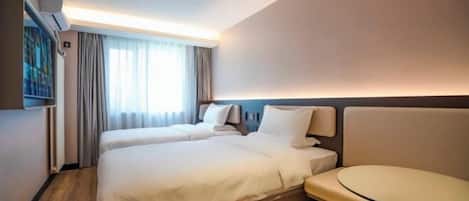 Ein Hotelzimmer mit zwei Betten, einem kleinen runden Tisch und einer Wandklimaanlage.