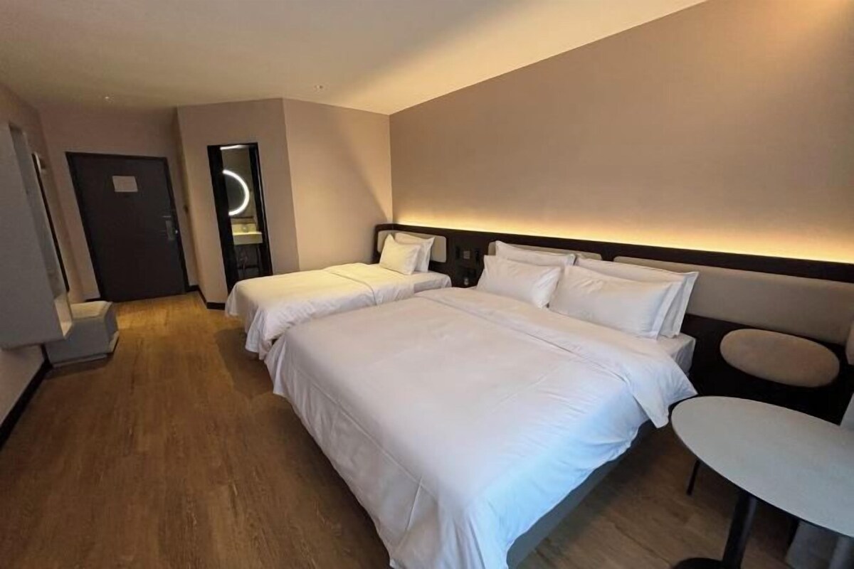 A hotel room with two beds, a small table, and a mirror.