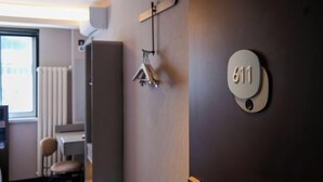 A room with a wall-mounted number plate labeled '611', a radiator, a chair, and a window with blinds. - HanTing Hotel (Tianjin Railway Station Italian Style Street) (Tianjin)