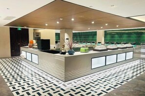 A hotel reception area with a modern design, featuring a central counter, seating area, and a patterned floor. - Fugang Hotel(Xuchang College High Speed Rail East Station Store) (Xuchang)