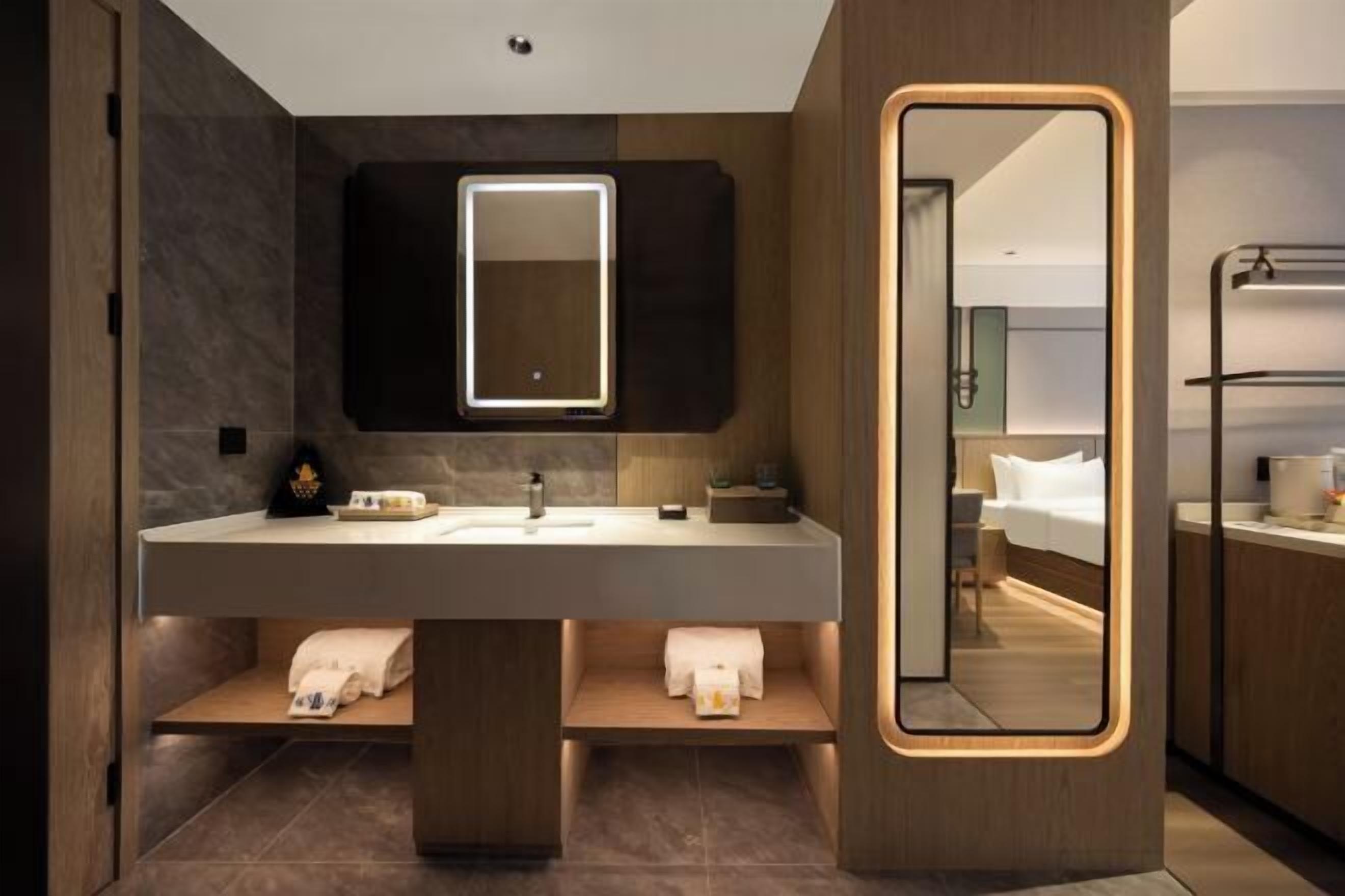 Un baño moderno con un espejo grande, un tocador con lavamanos y un perchero para toallas.