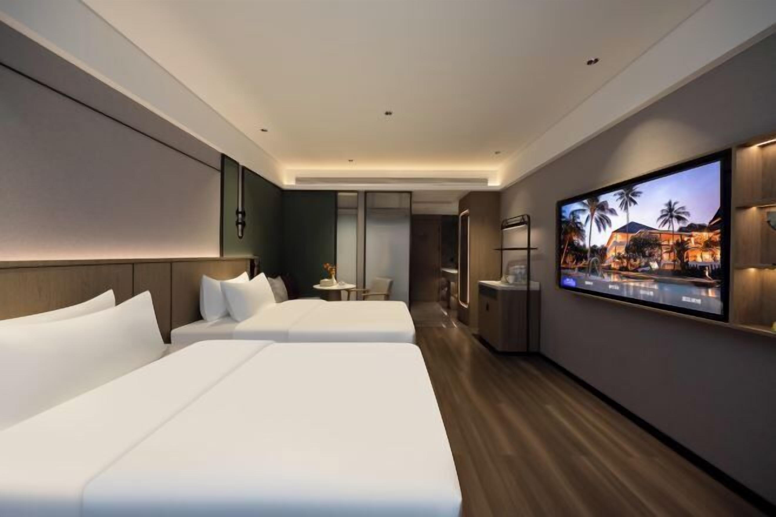 Une chambre d’hôtel moderne avec deux lits, une télévision et une petite table.