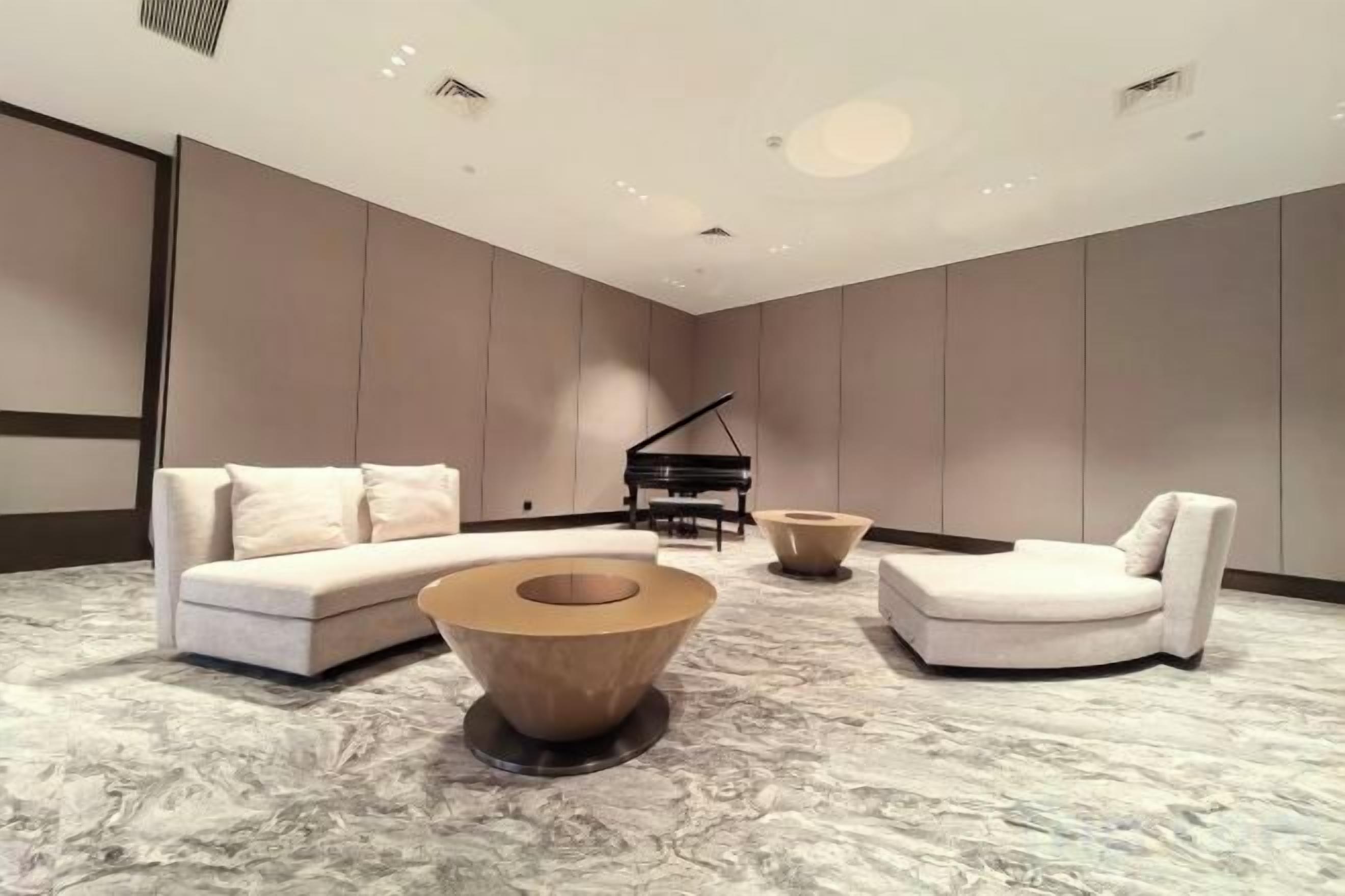 A modern living room with a sectional sofa, a round coffee table, a piano, and a chaise lounge.