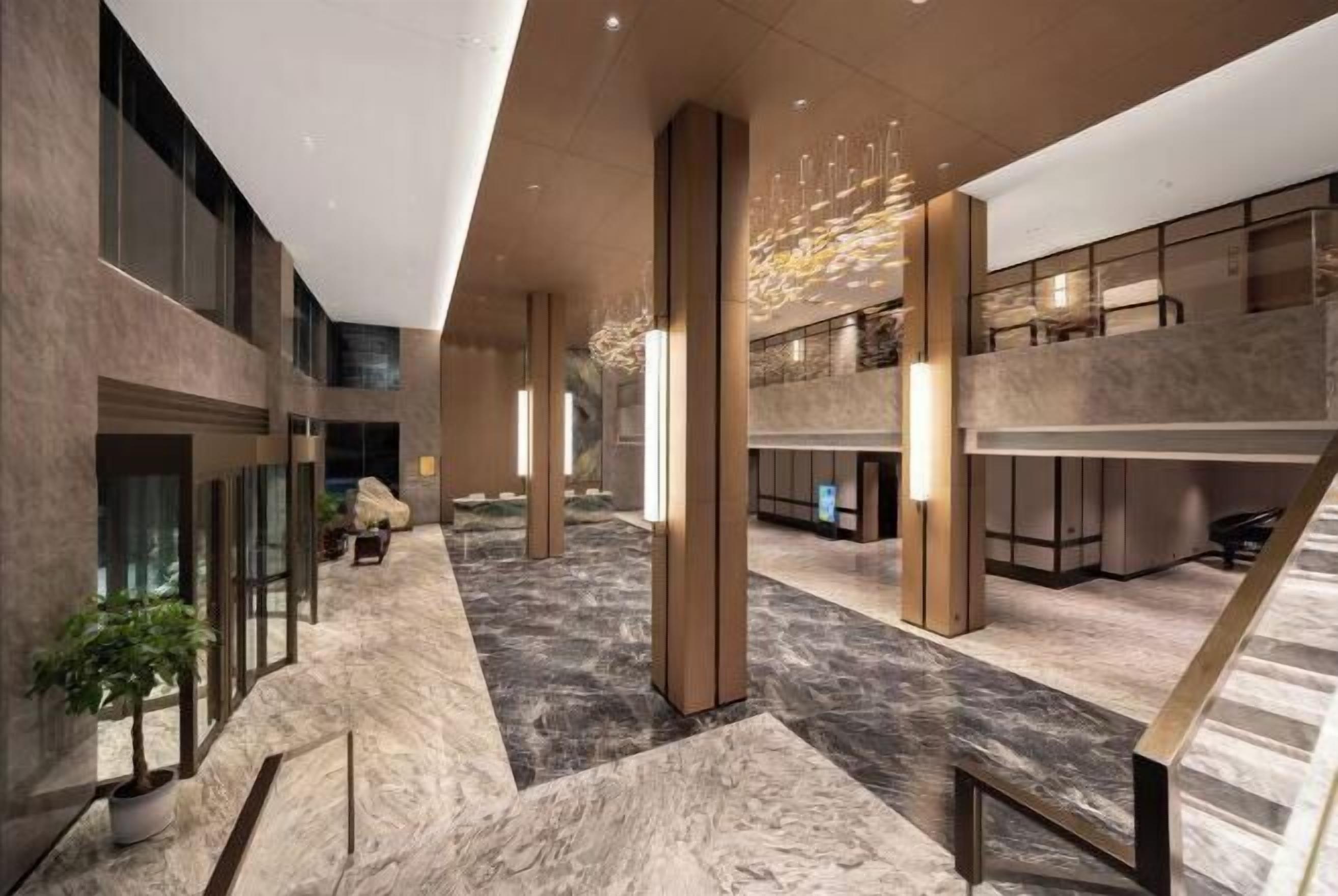A spacious lobby with marble flooring, large columns, and modern lighting fixtures.