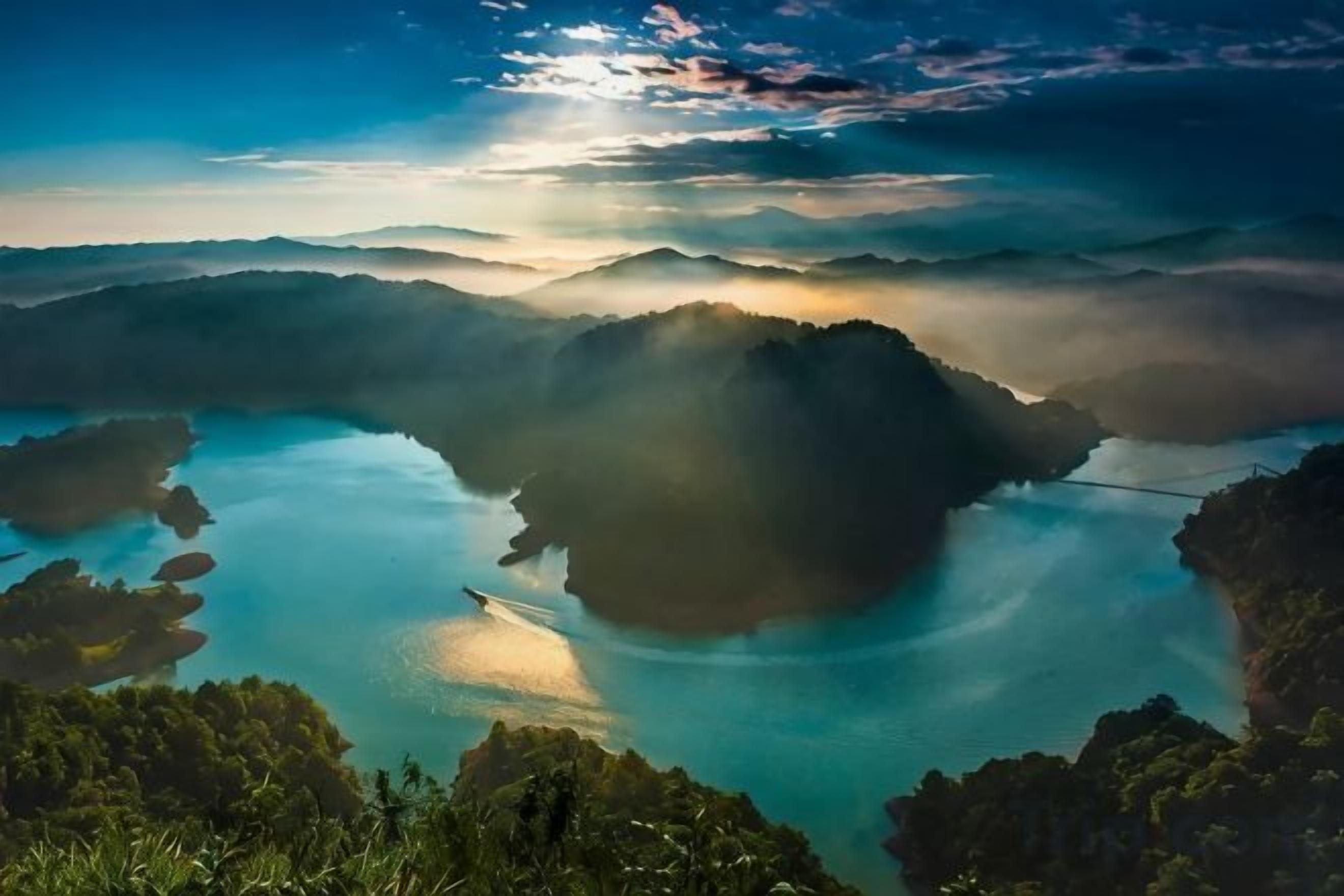 A panoramic view of a coastal landscape with a body of water surrounded by hills and vegetation.