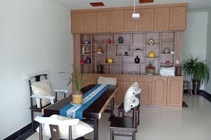 Un comedor con una mesa de madera, sillas y un aparador con estantes que contienen varios objetos decorativos.