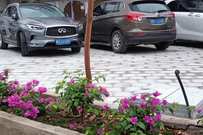 A parking area with vehicles and a flower bed with pink flowers. - Taining Dajinhu Xiuzhen Homestay (Taining)