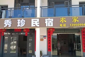 A two-story building with a signboard displaying the name and contact number. - Taining Dajinhu Xiuzhen Homestay (Taining)