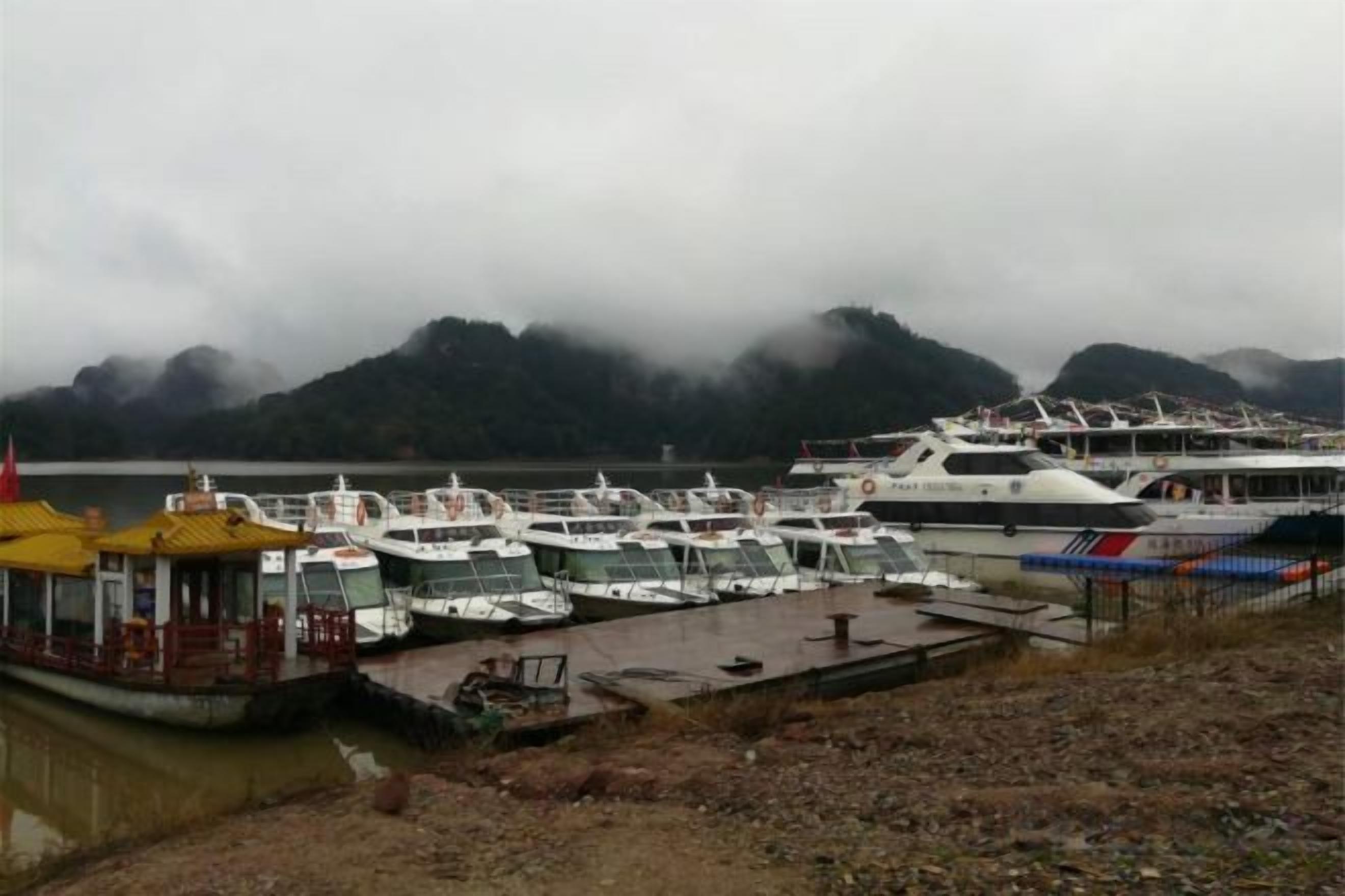 Un puerto deportivo con barcos amarrados, un muelle y montañas al fondo.