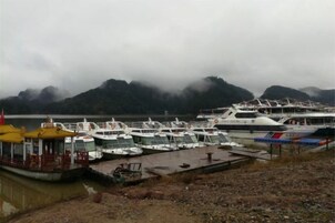 Un puerto deportivo con barcos amarrados, un muelle y montañas al fondo.