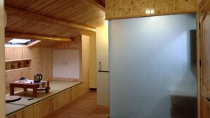 A wooden interior with a high ceiling, a skylight, and a kitchenette area with cabinets and a countertop.