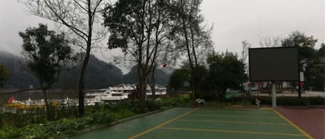 A parking area with green and yellow markings, surrounded by trees and a view of mountains.