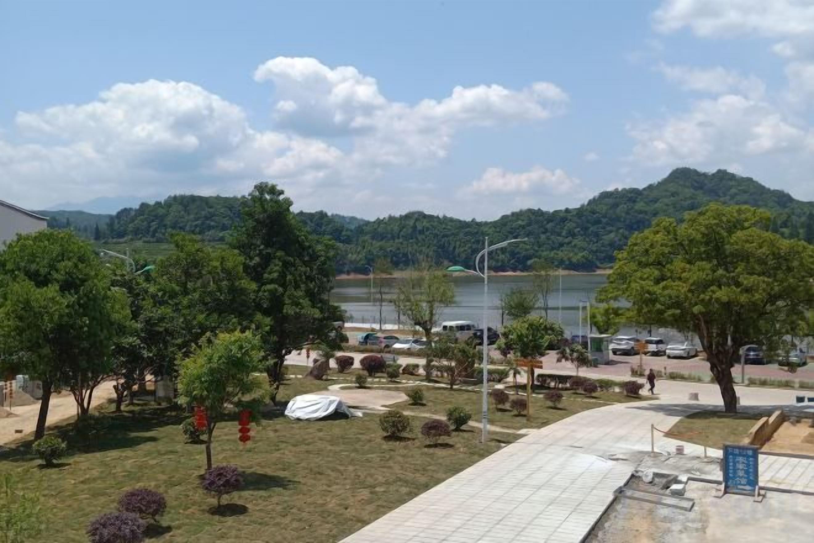 A view of a parking area with a lake and hills in the background.