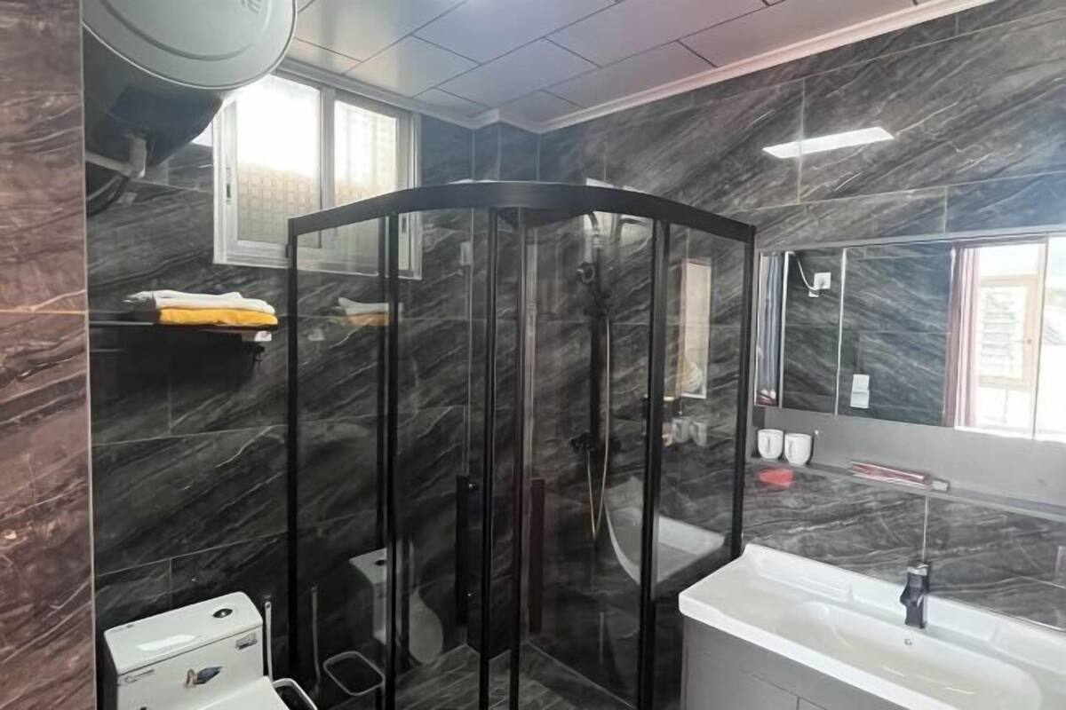 A modern bathroom with a glass-enclosed shower, a white sink, and a marble backsplash.