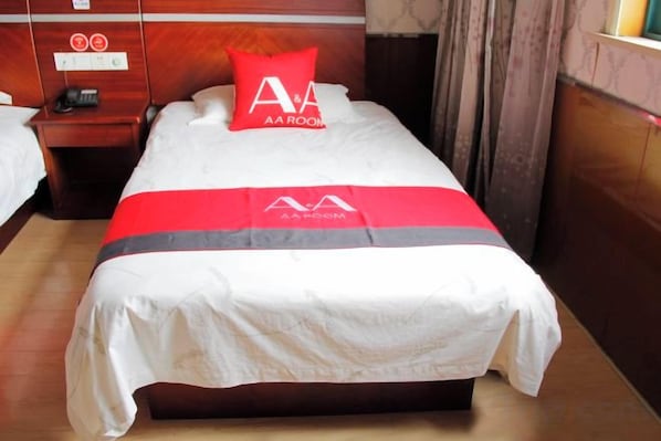 A hotel room with a bed, a nightstand, and a red pillow with a logo. - AA Room Hotel (Shanghai Donglin Temple) (Shanghai)