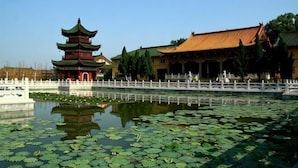 A traditional pagoda with a reflection in a pond, a white fence, and a building with a tiled roof. - AA Room Hotel (Shanghai Donglin Temple) (Shanghai)