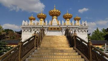 A temple entrance with a staircase leading up to a structure with golden domes.