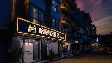 A hotel with a prominent illuminated sign, multiple floors, and a courtyard with potted plants.