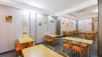A conference room with multiple tables and chairs, white walls, and ceiling lights.