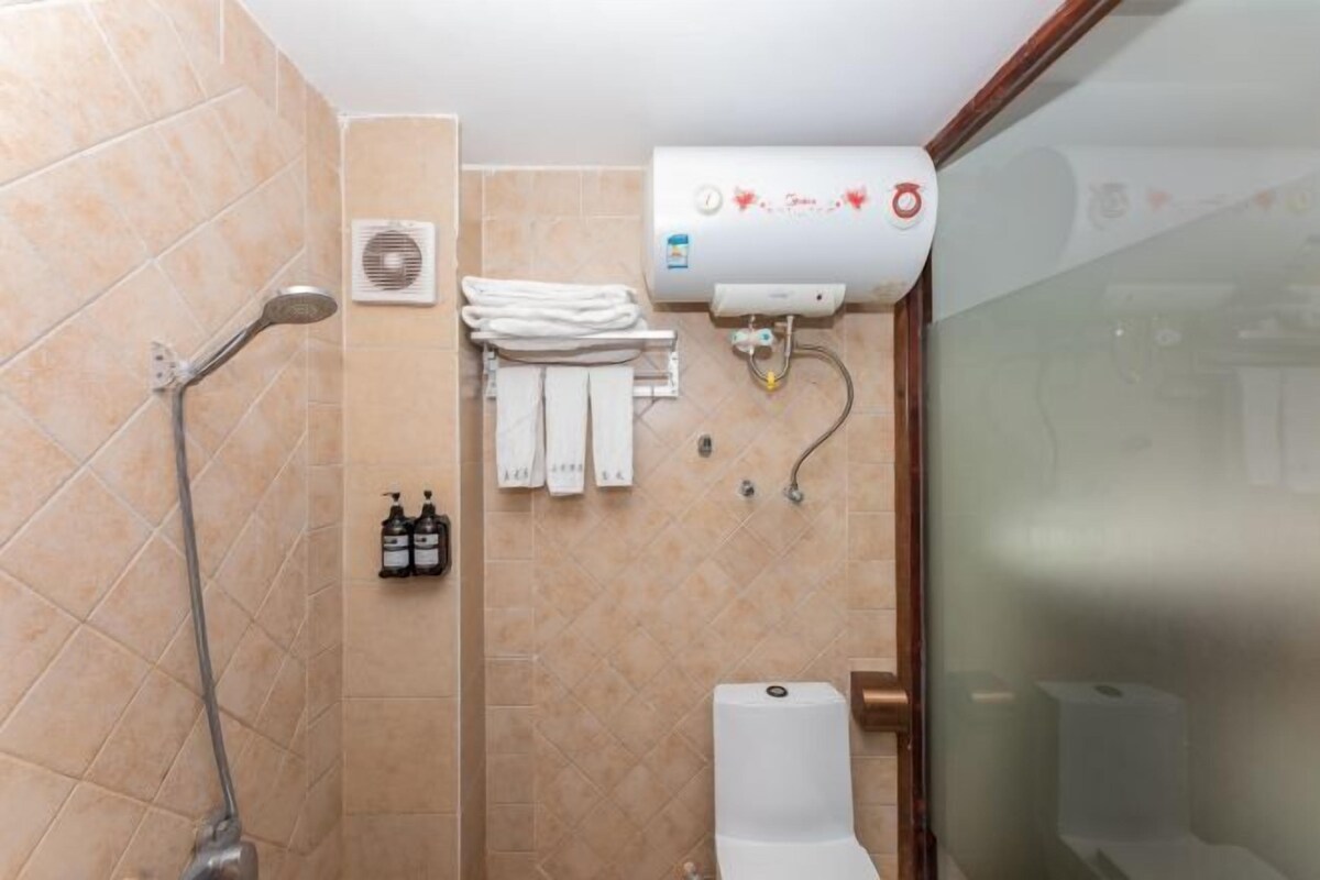 Un baño con ducha, inodoro, toallero y calentador de agua.