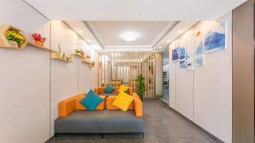 A hallway with a sofa, decorative items, and artwork.