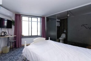 A hotel room with a bed, a desk with a computer, a television, a window with curtains, and a bathroom with a toilet and shower. - 100 Inn (Shanghai Pudong Lingang University Town store) (Shanghai)
