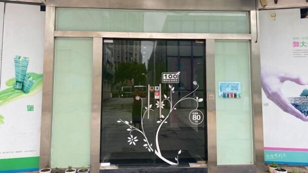 A hotel entrance with a glass door, a digital signboard, and a floral sticker design.