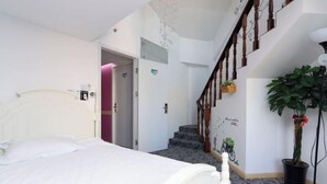 A hotel room with a bed, a staircase, and a potted plant.