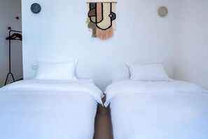 A room with two beds, white bedding, a wall hanging, and a small round mirror. - Haisong Muwu Resort (Dongshan County)