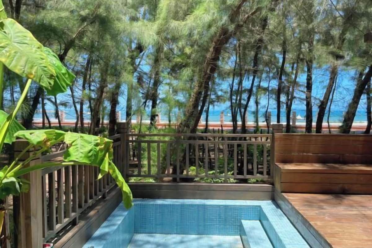 A swimming pool with a wooden deck and a view of the ocean.