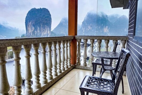 Ein Balkon mit Tisch, Stühlen, Geländer und Blick auf Berge.