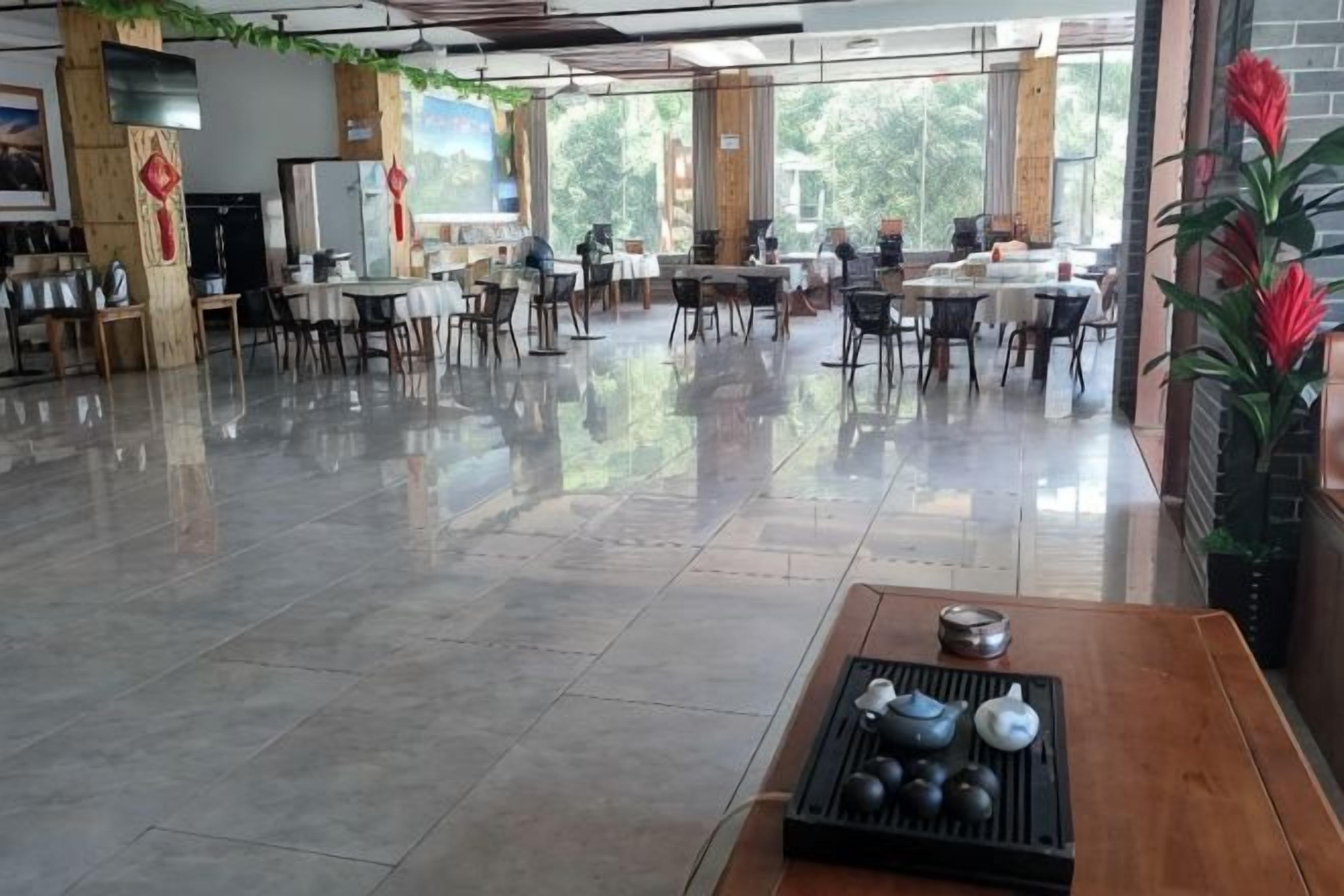 A spacious indoor area with tables and chairs, large windows, and a polished floor.