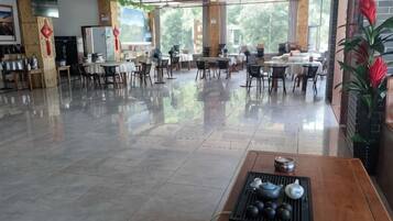 A spacious indoor area with tables and chairs, large windows, and a polished floor.