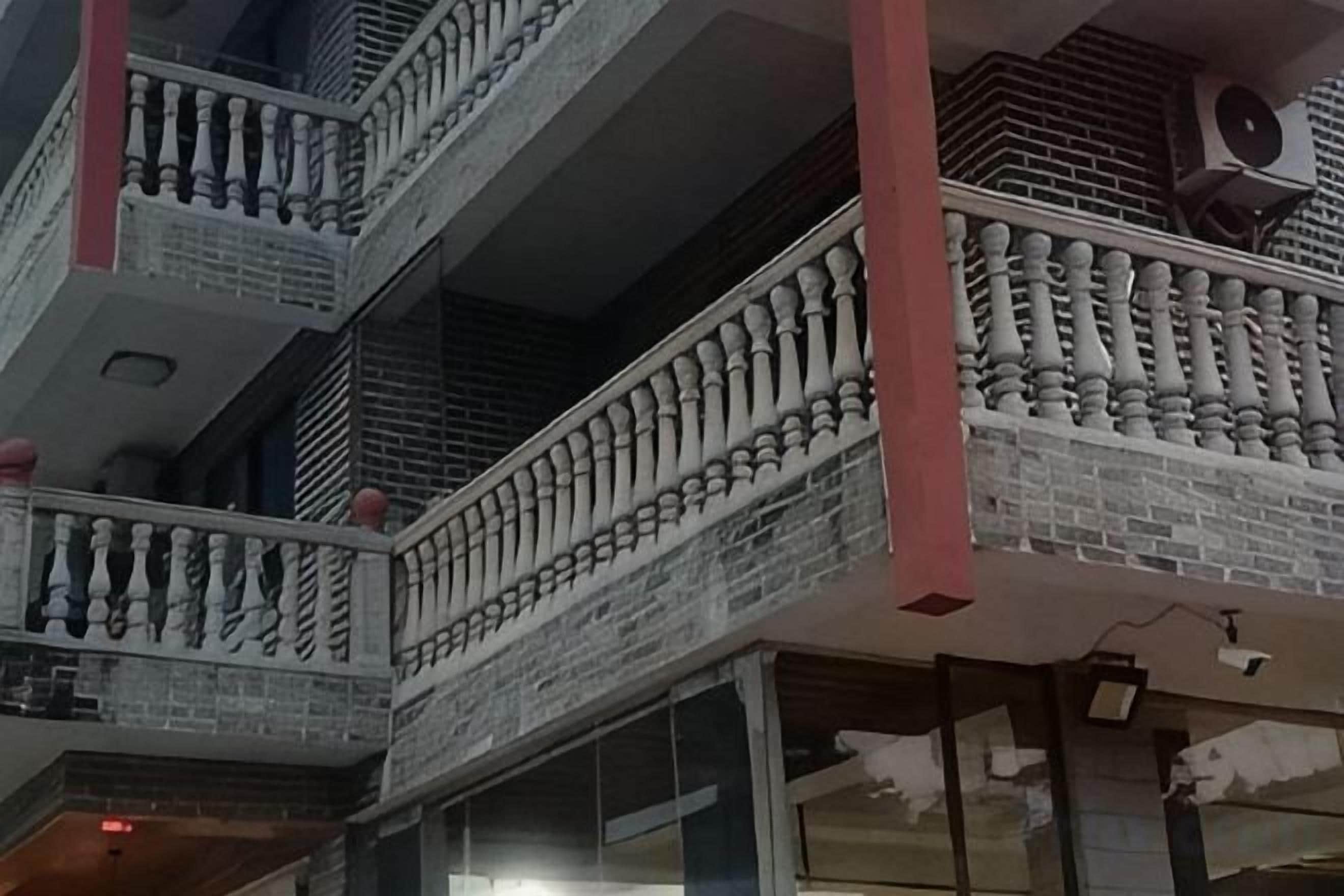 A multi-story building with balconies featuring railings and air conditioning units.