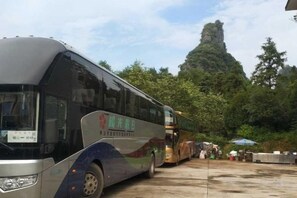 Un autobus est garé dans un parking, avec une chaîne de montagnes en arrière-plan.