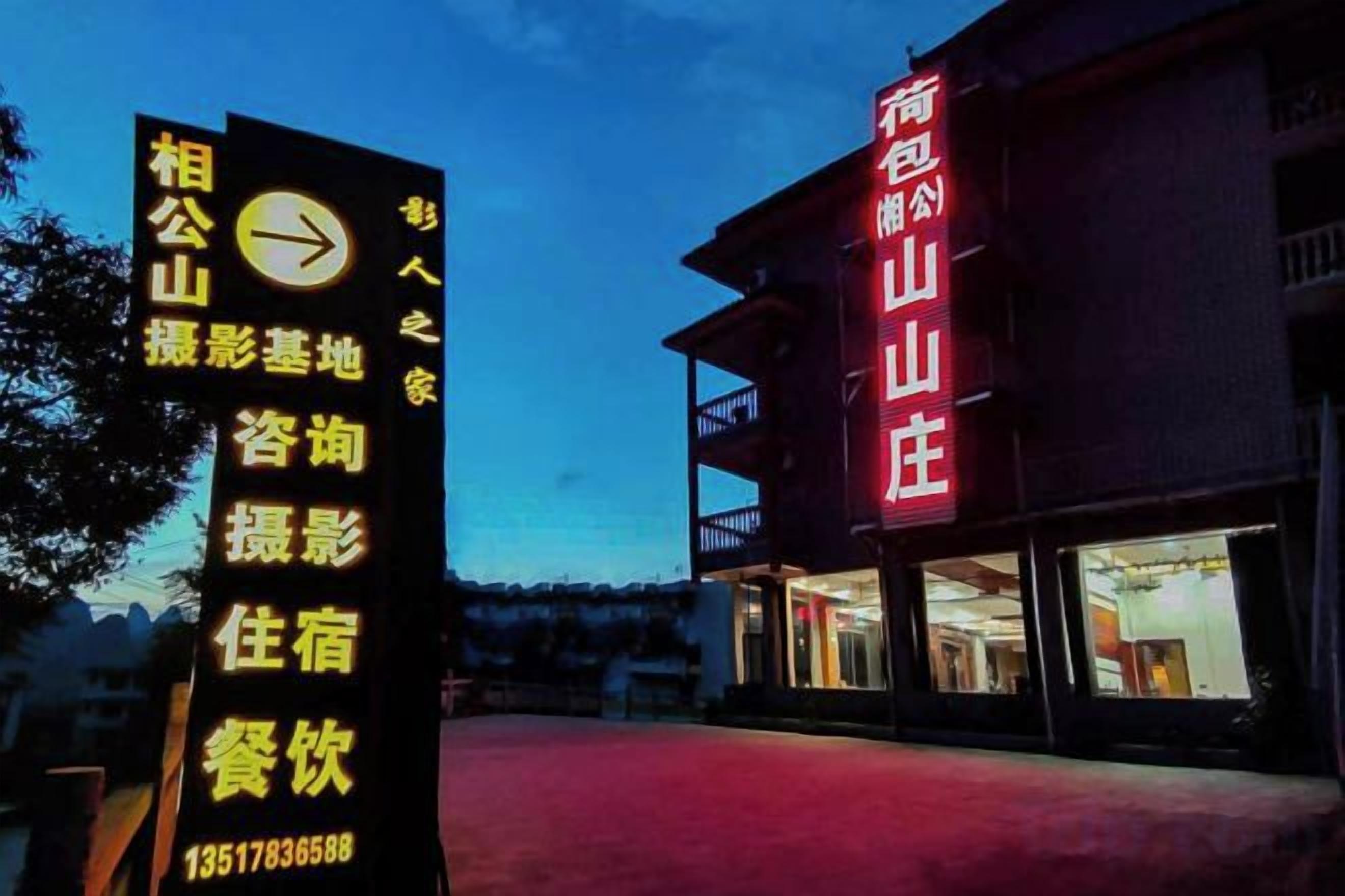 Un hotel con un letrero rojo llamativo, un cartel negro con letras amarillas y una alfombra roja que conduce a la entrada.